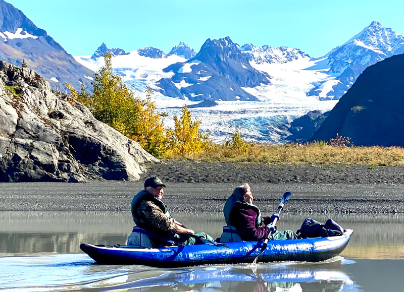 A couple paddling their kayaking on a beautiful sunny day with Grewingk Glacier in the background. 
