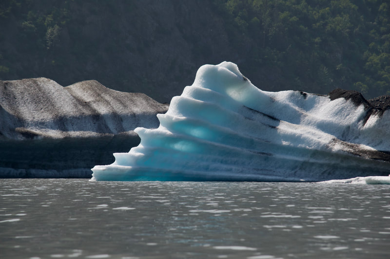 Sunlight shining through a  beautiful, blue, multi-layered iceberg on the Grewingk Glacier Lake. 